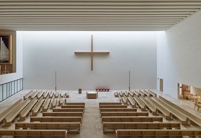 an empty church with benches and a cross on the wall