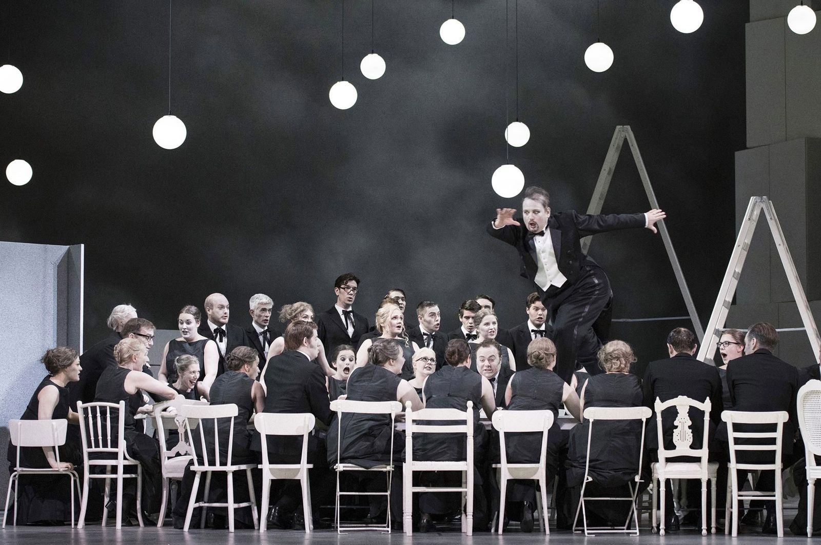 a man in a tuxedo standing on a stage in front of a group