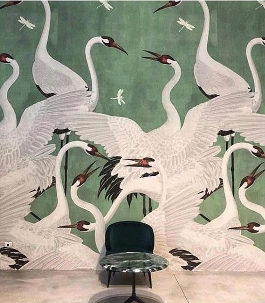 a chair sitting in front of a wall with swans on it