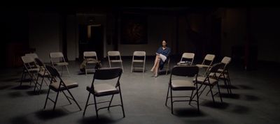 a woman sitting on a chair in a dark room