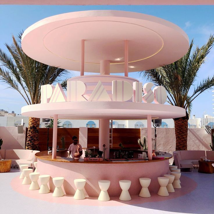 a pink building with a bar and palm trees in the background