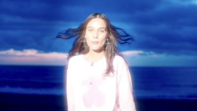 a woman with long hair standing on a beach