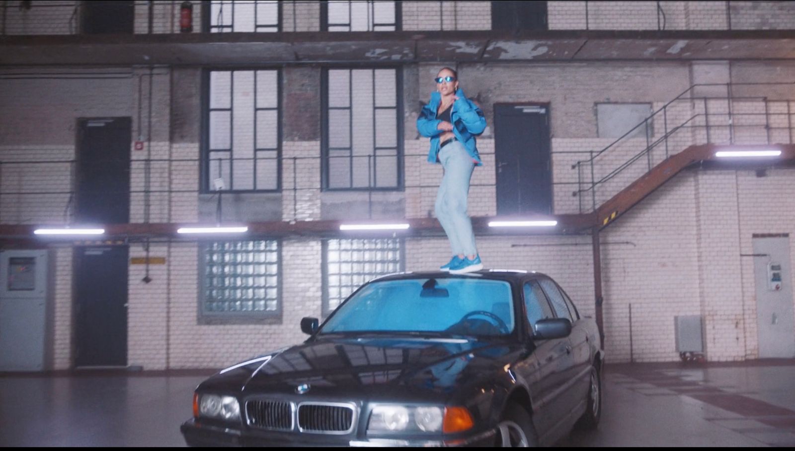 a man standing on top of a car in front of a building