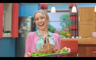 a woman holding a tray of food in a kitchen