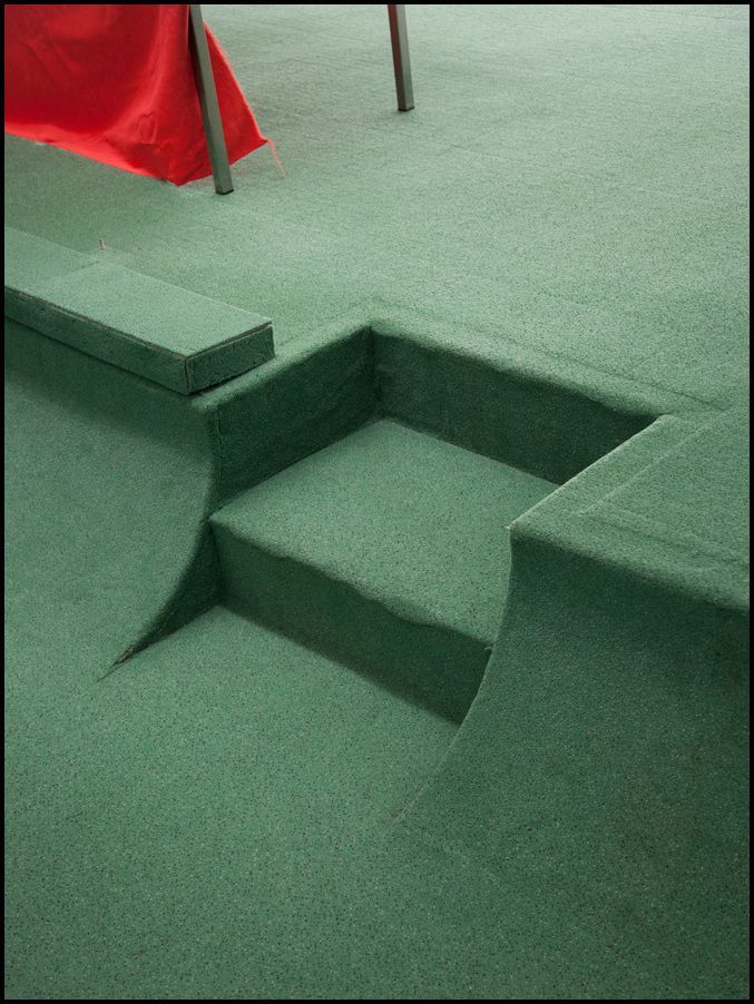 a skateboarder doing a trick on a green ramp