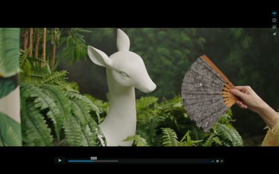 a person holding a fan next to a statue of a deer