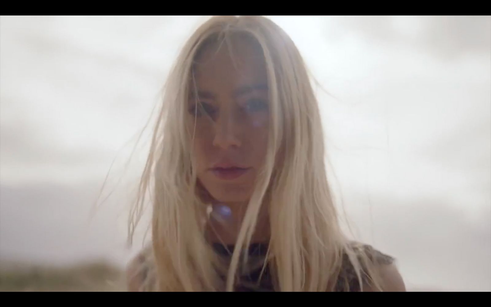 a woman with long blonde hair standing in front of a sky