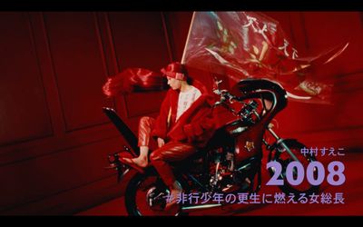 a person sitting on a motorcycle with a red background