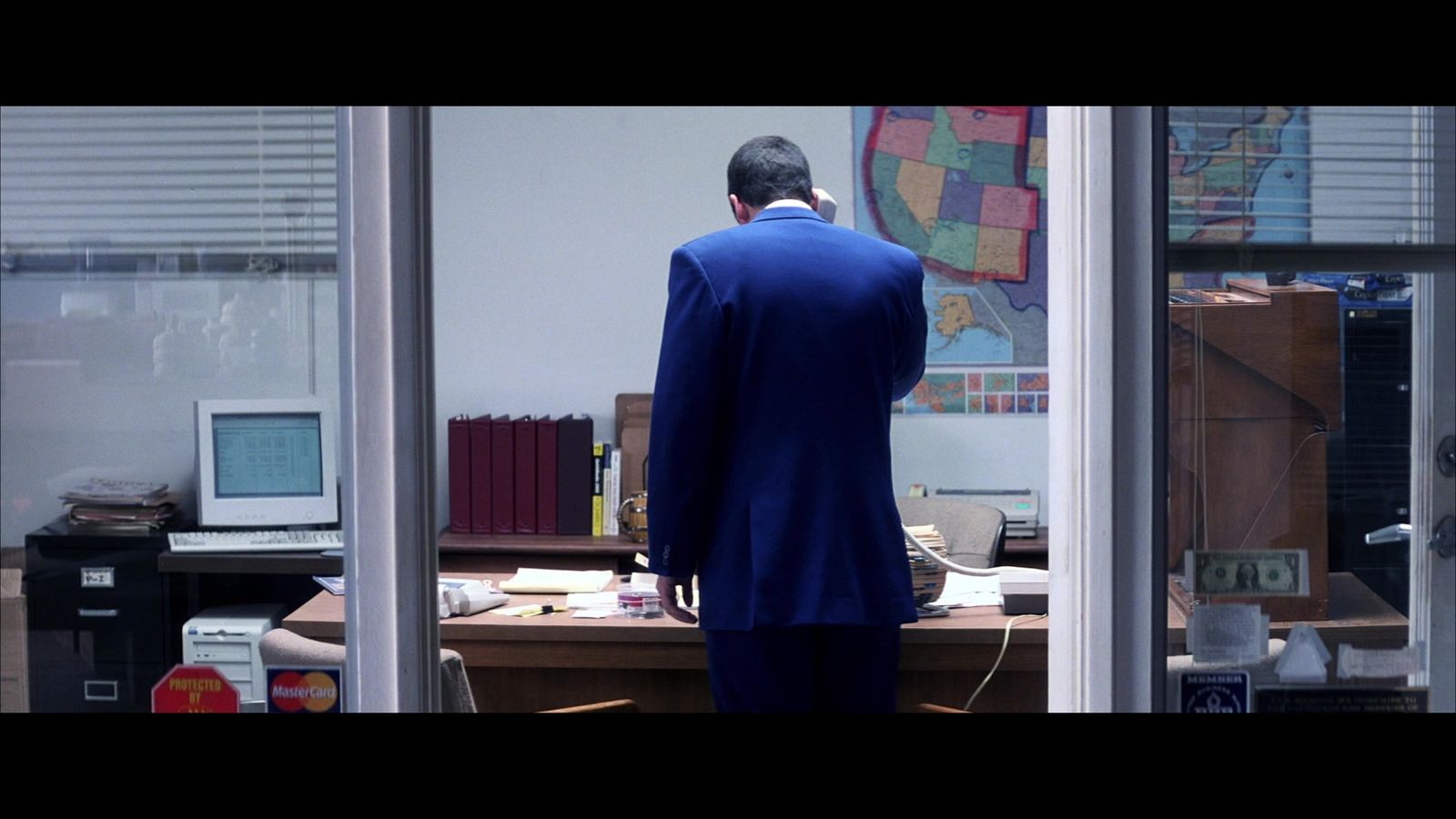 a man in a blue suit standing in front of a desk