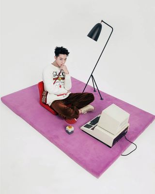 a man sitting on a rug with a laptop on it