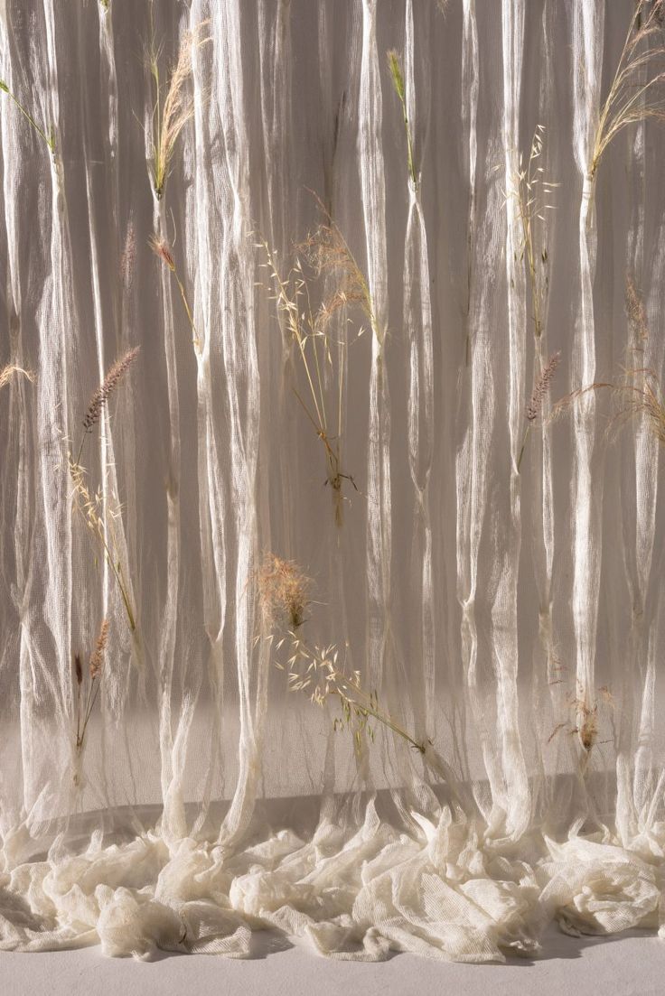 a white curtain with some plants growing out of it