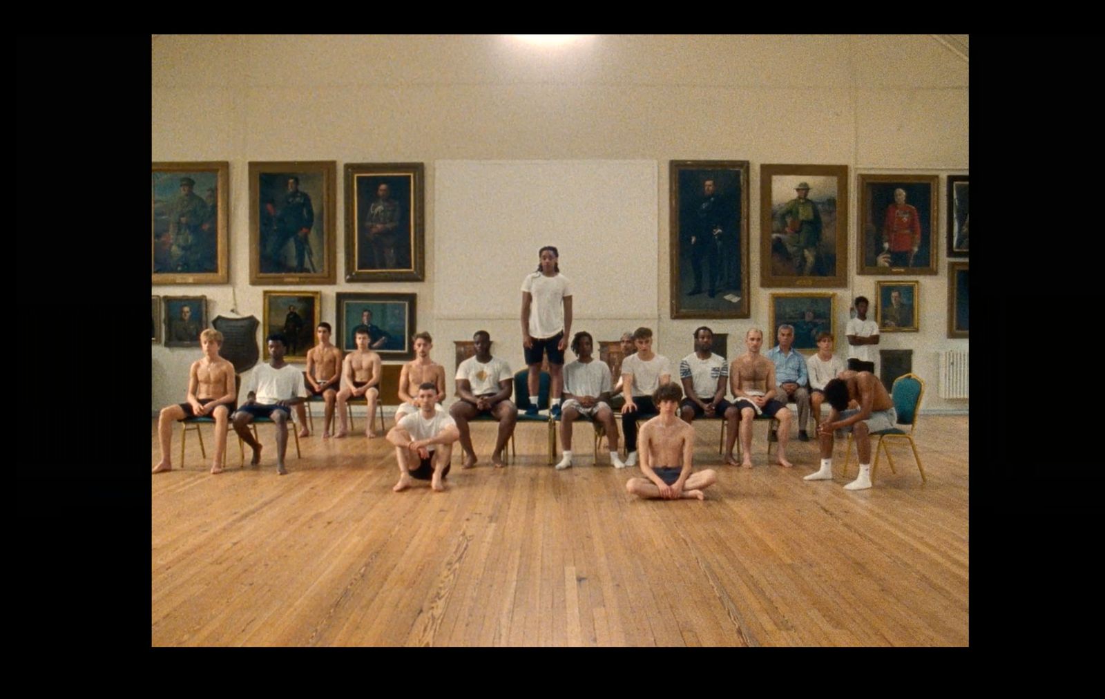 a group of people sitting in a room with paintings on the wall