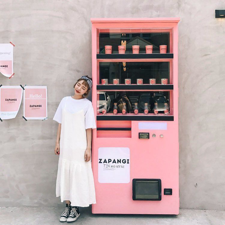 a woman standing next to a pink vending machine