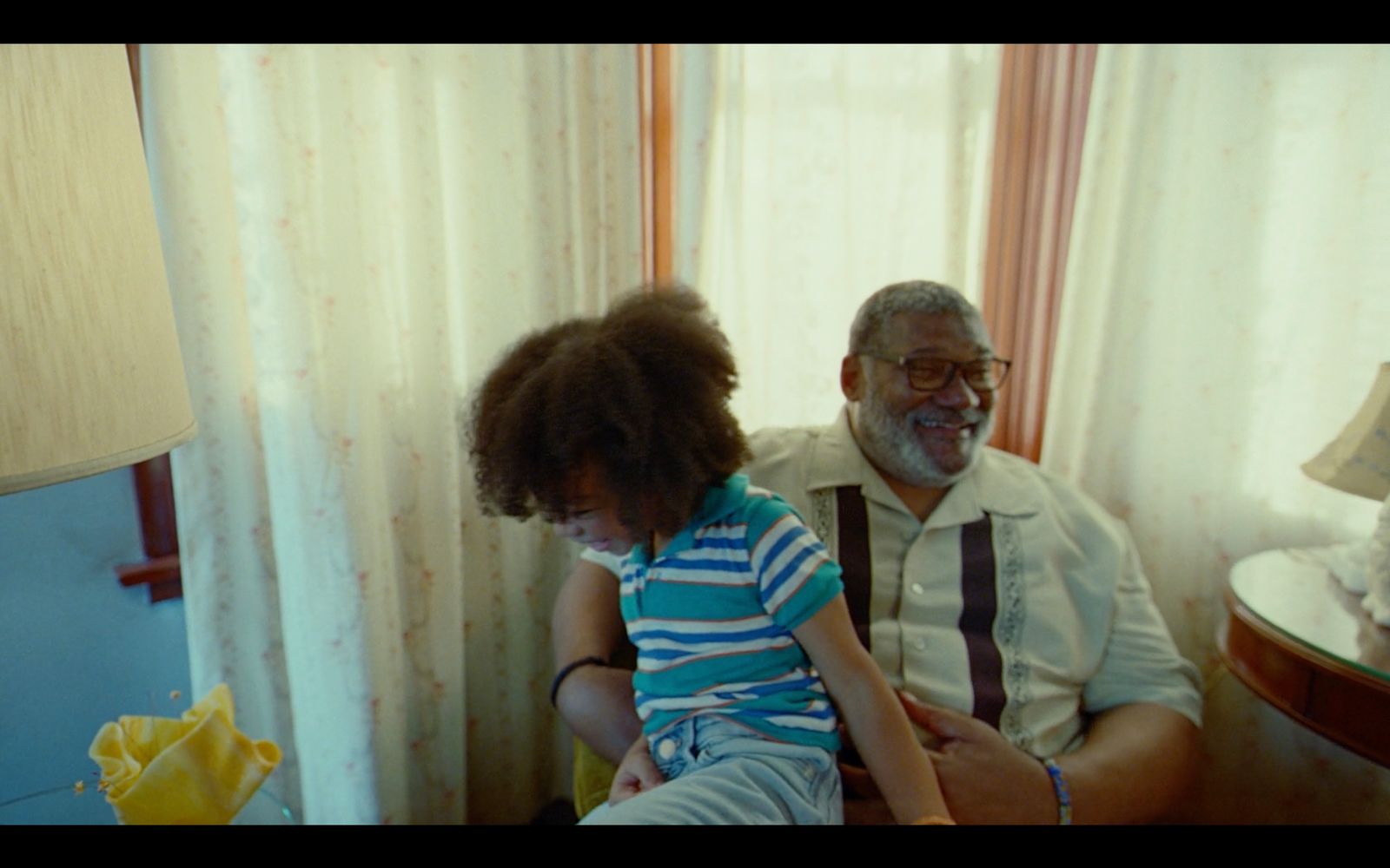 a man sitting next to a little girl on a bed