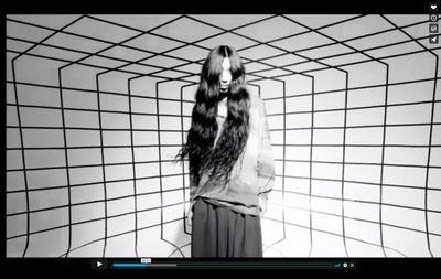 a woman with long hair standing in front of a wall