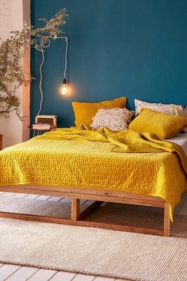 a bed with a yellow bedspread and pillows