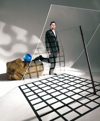 a man in a suit standing in front of a large rock