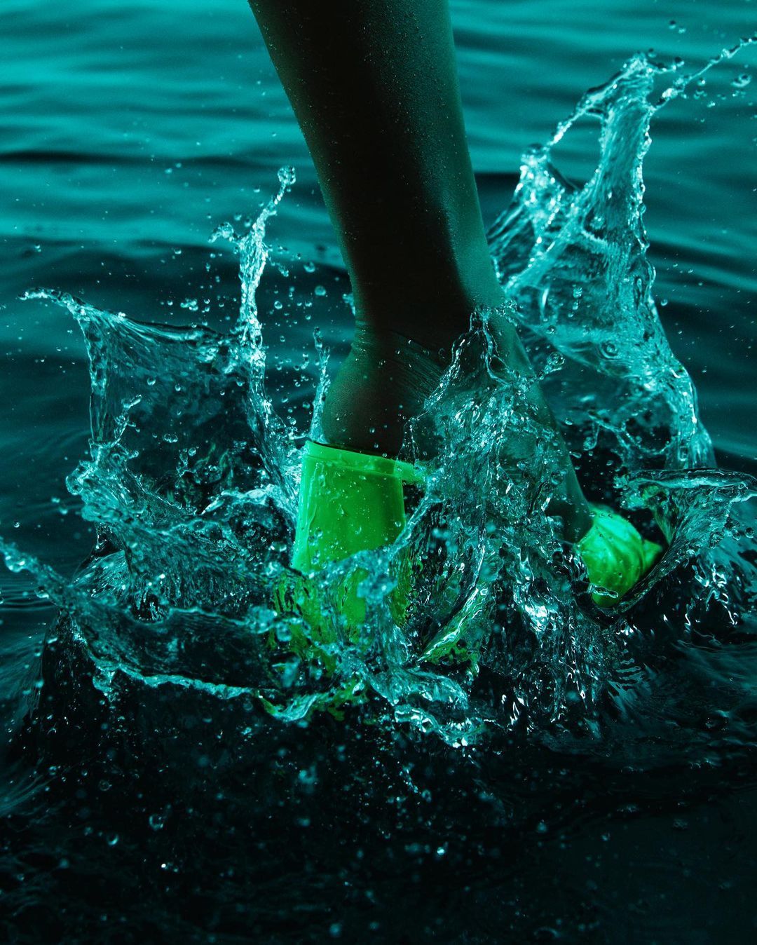 a person in green shoes splashing in the water