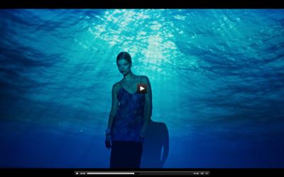 a woman in a blue dress standing under water