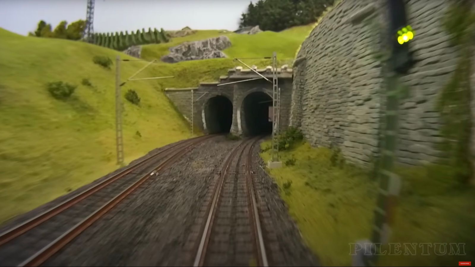 a train traveling through a tunnel next to a lush green hillside