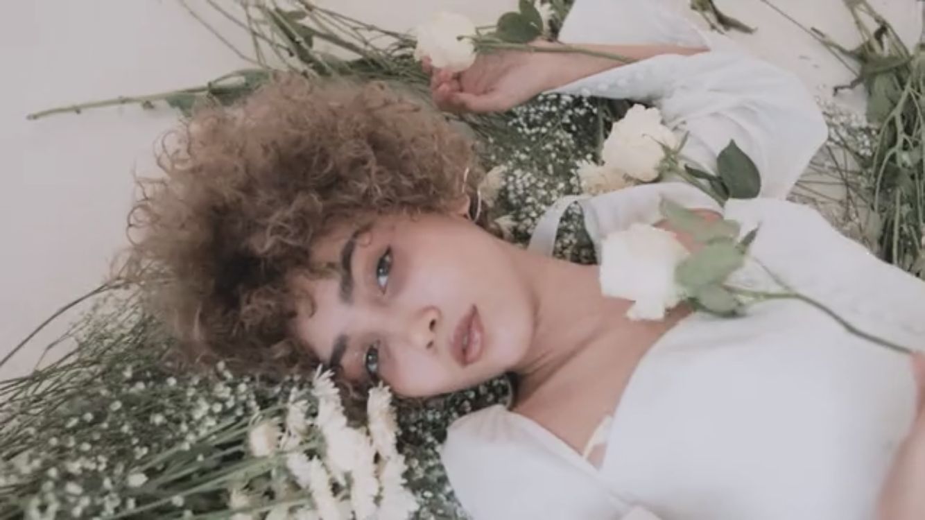 a woman laying on the ground with flowers in her hair