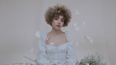 a woman with curly hair wearing a white dress