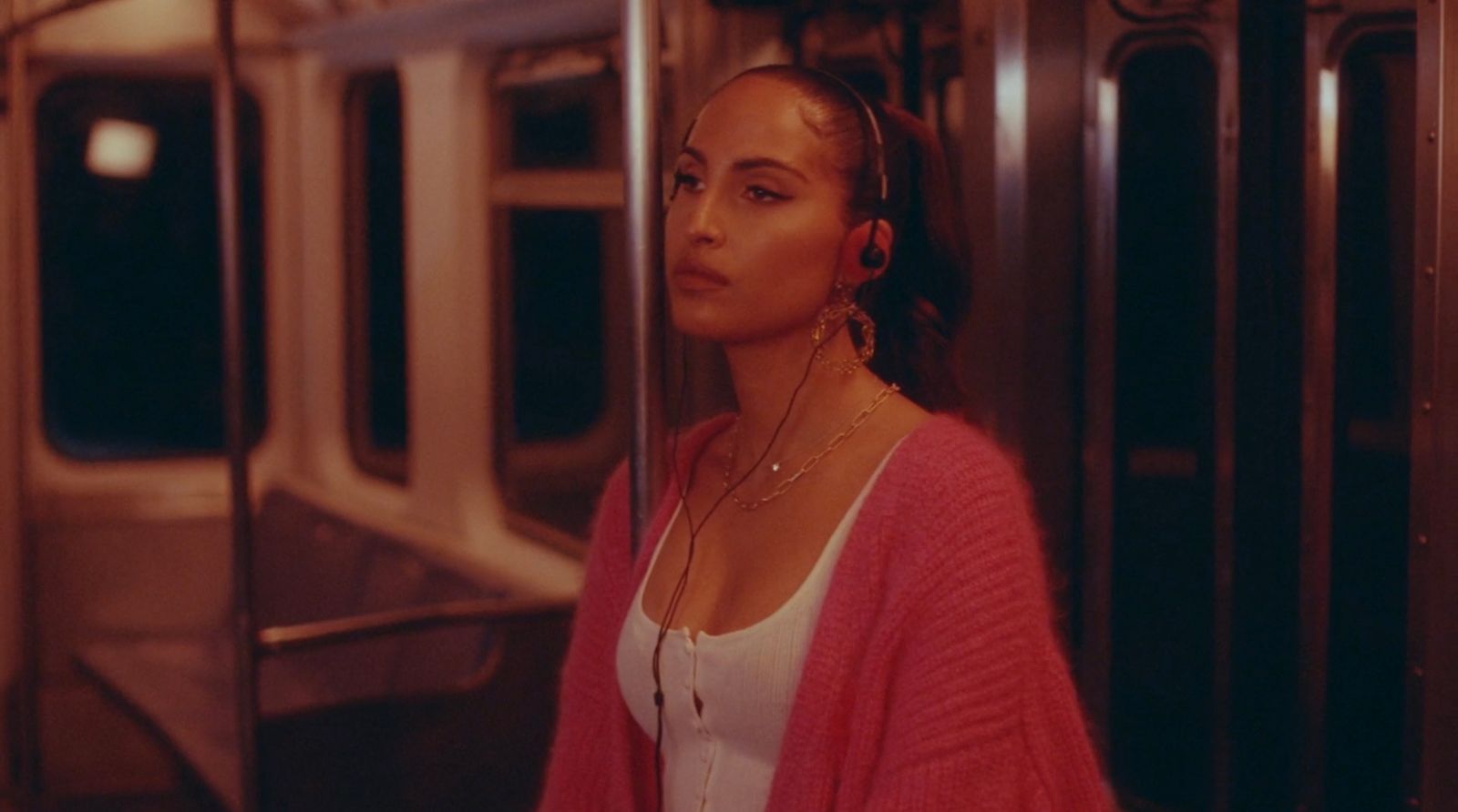 a woman in a pink cardigan standing on a train