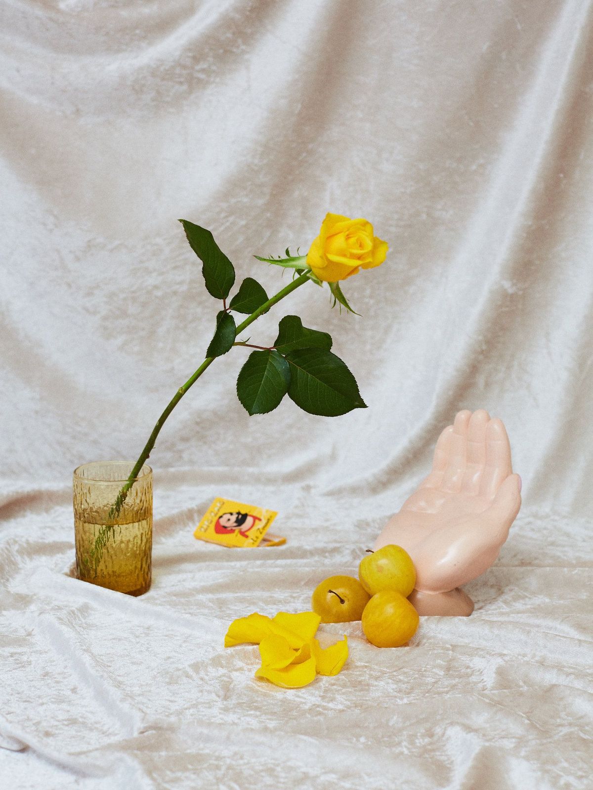 a yellow rose in a vase next to rubber ducks