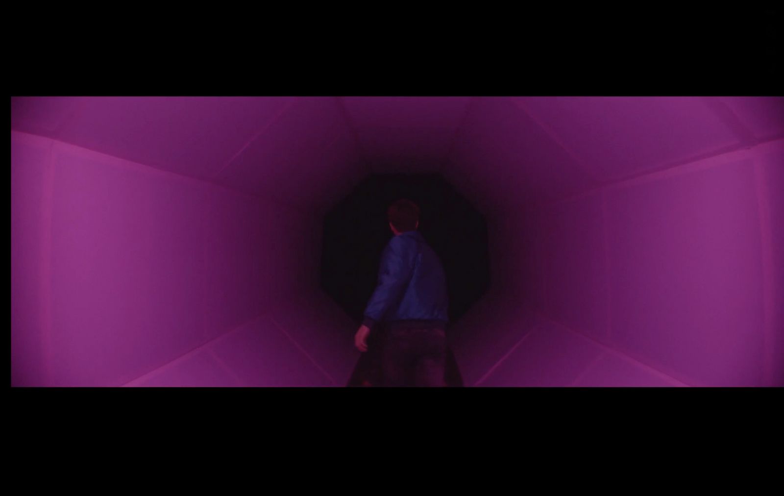 a man is standing in a purple tunnel