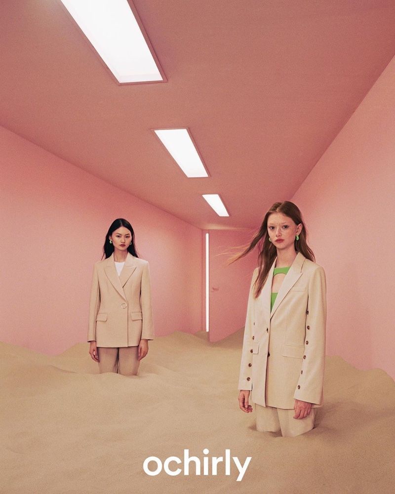 two women standing in a room with pink walls