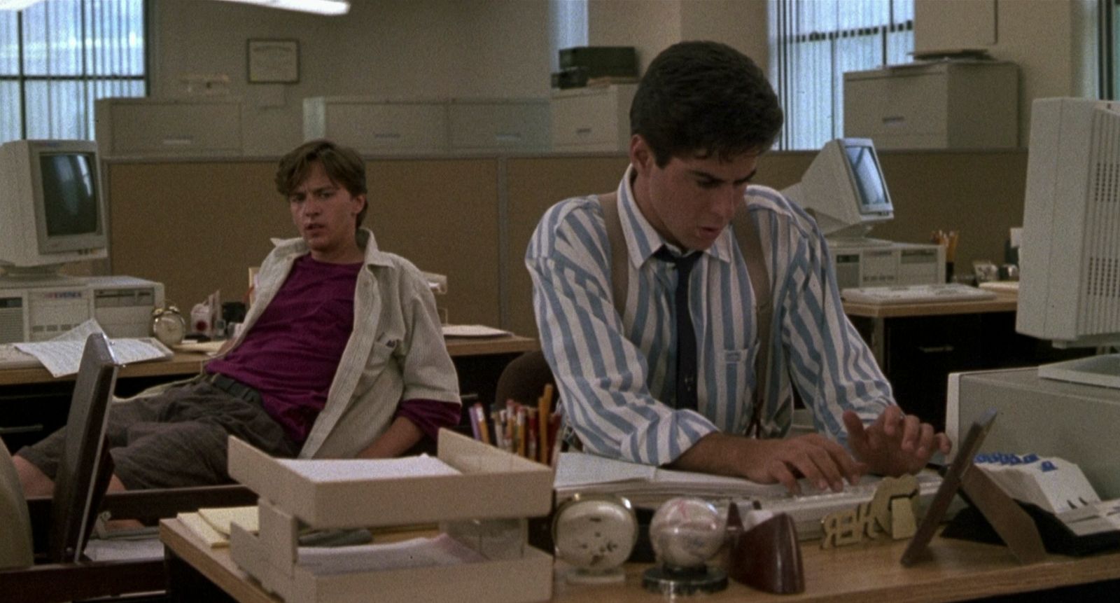 two men sitting at a desk in an office