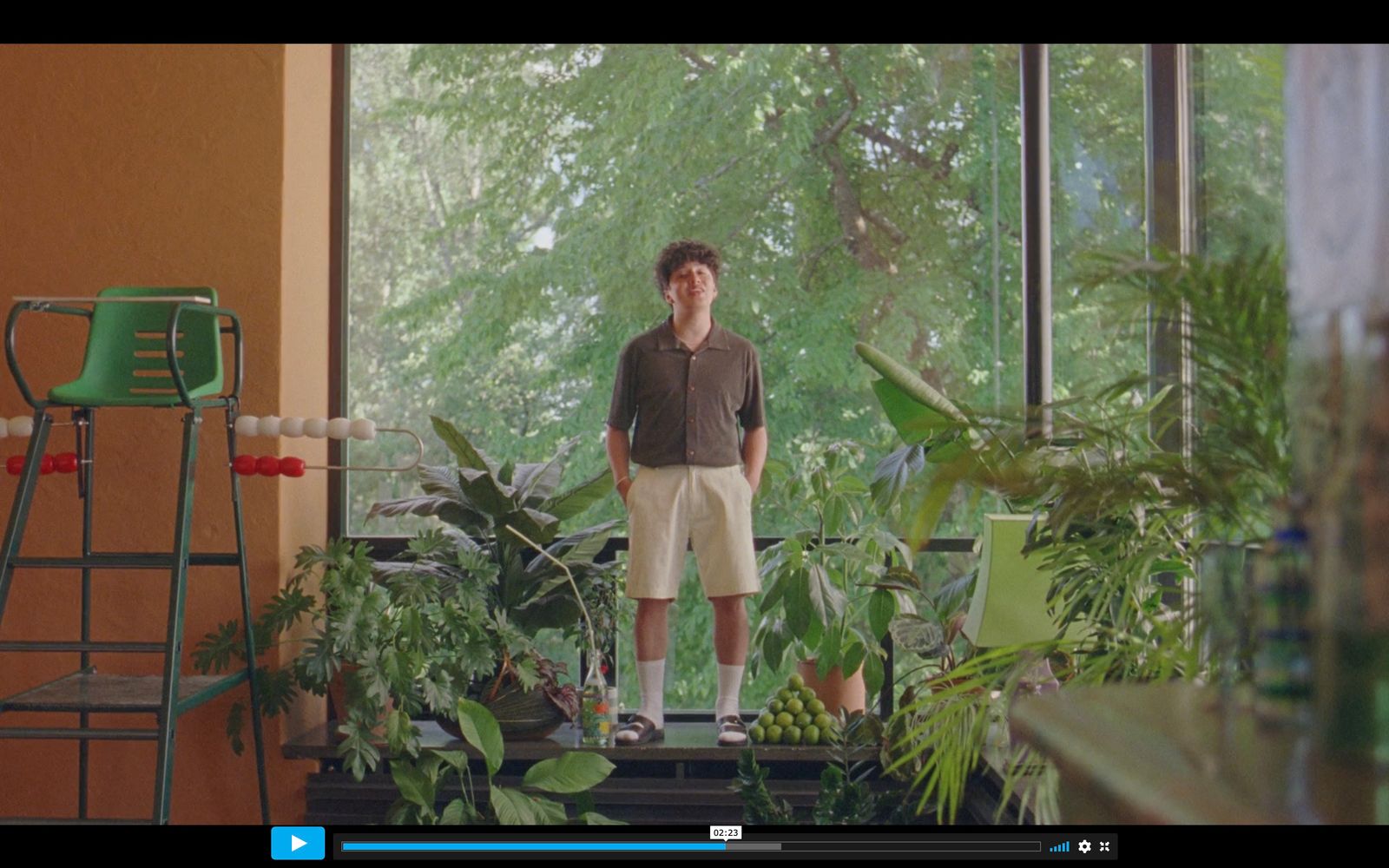 a man standing in front of a window in a room filled with plants