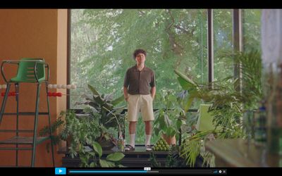 a man standing in front of a window in a room filled with plants