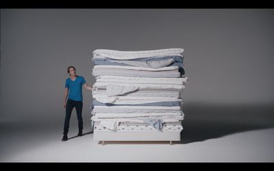 a woman standing next to a stack of folded clothes