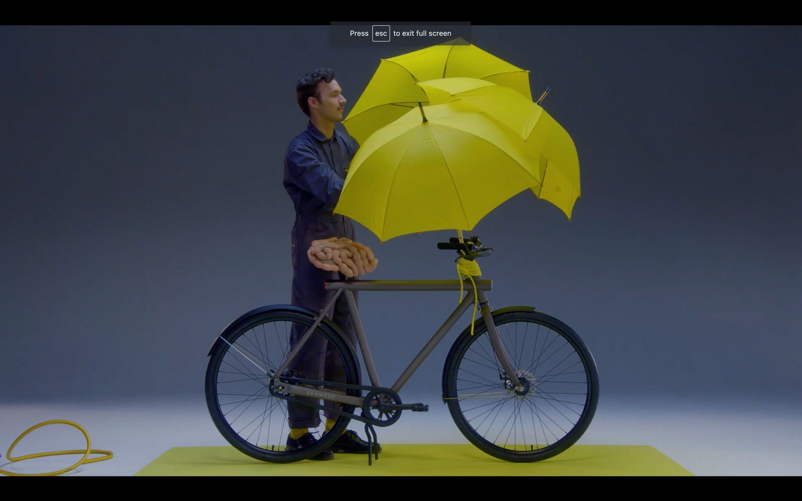 a man holding a yellow umbrella on top of a bike