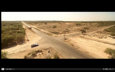 a car driving down a dirt road in the middle of a desert