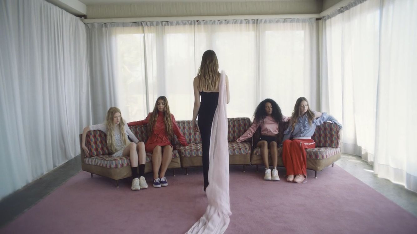 a woman standing in front of a group of women sitting on couches