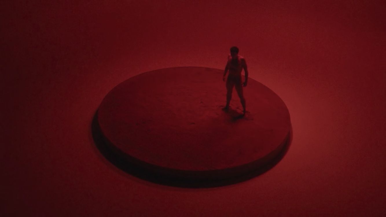 a man standing on top of a round object in a red room