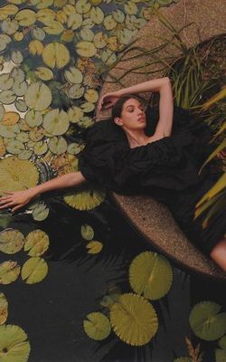 a woman laying on a bench in a pond of water lilies