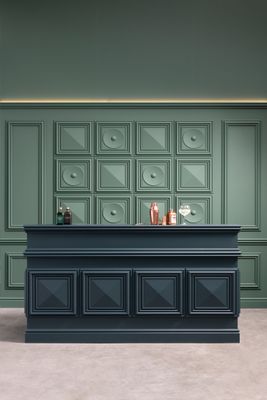 a bar with a black counter and a green wall