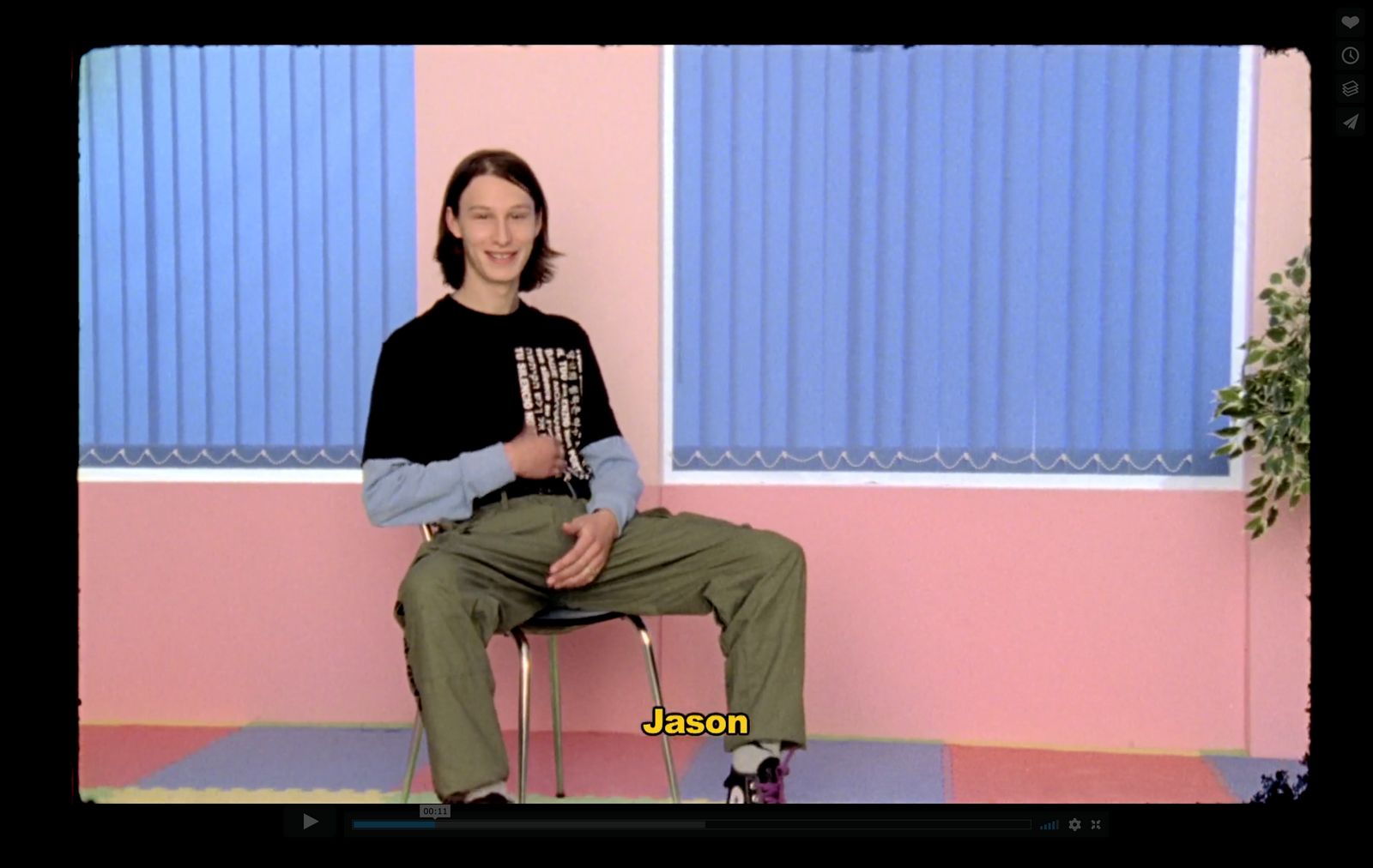 a man sitting on a chair in front of a pink wall