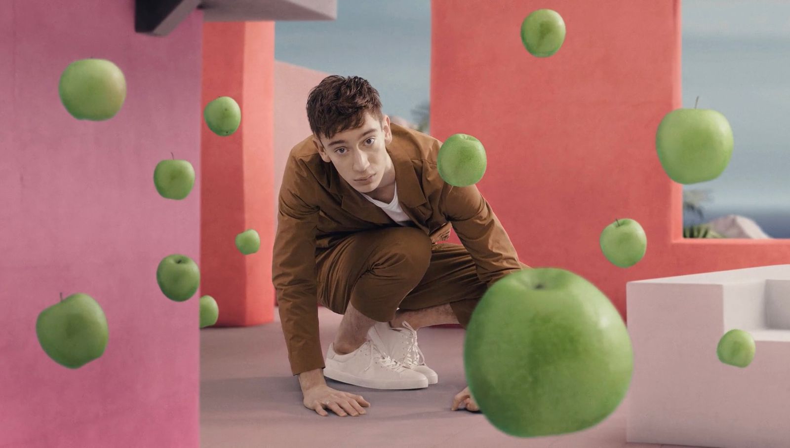 a man kneeling down next to a green apple