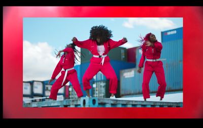 a group of women in red jumpsuits jumping in the air