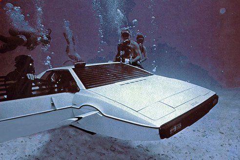 a futuristic car floating in the ocean with two scuba divers