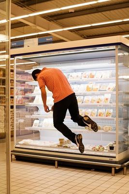 a man in an orange shirt is jumping in front of a display case