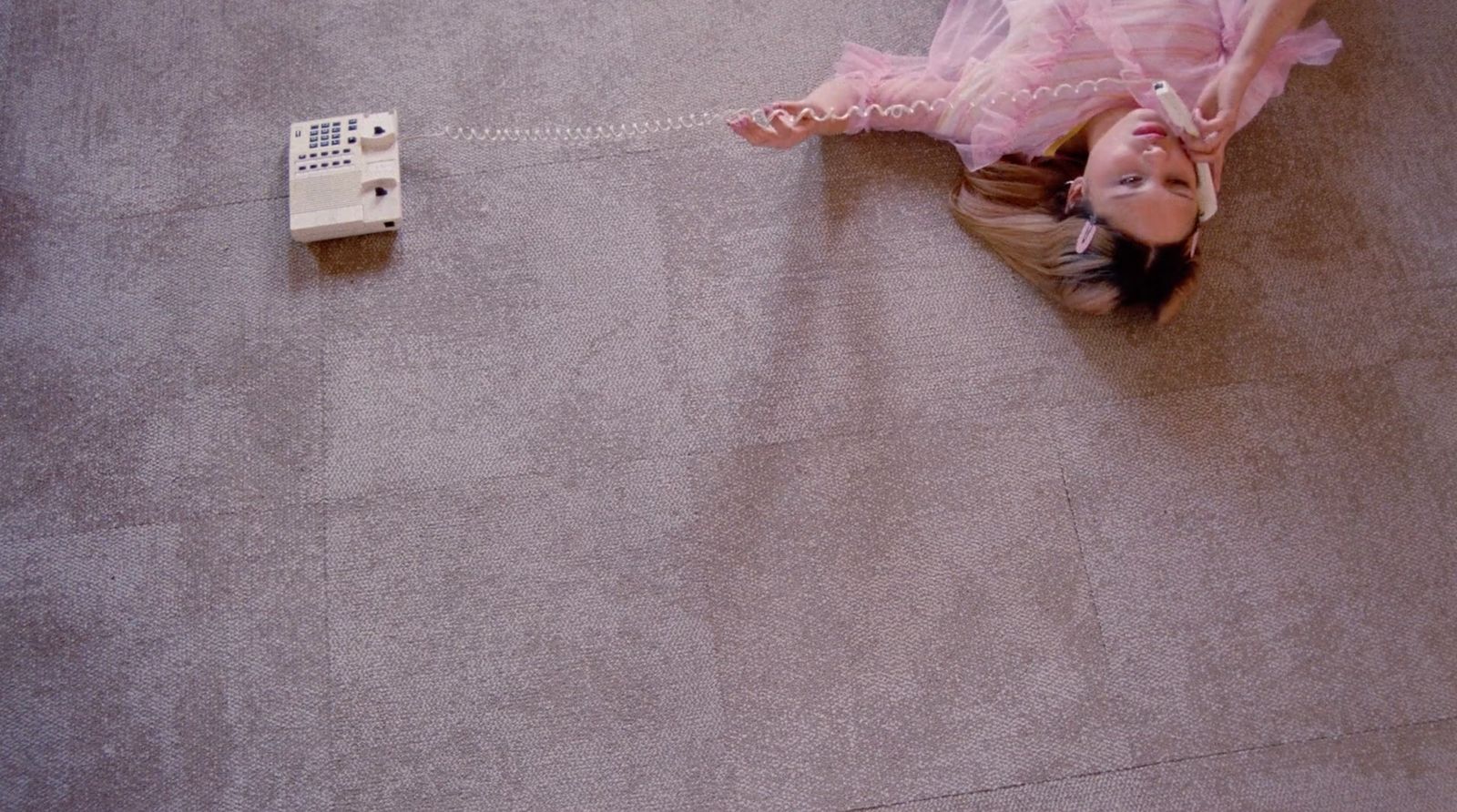 a little girl laying on the floor next to a remote control