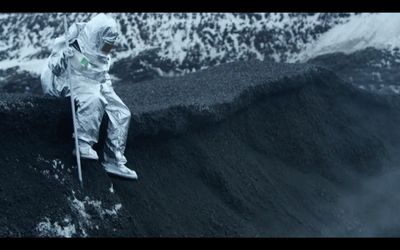 a man in a space suit sitting on top of a mountain