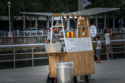 a man standing behind a food cart selling drinks