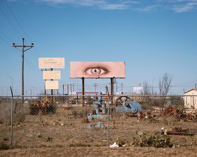 a large sign with an eye on it in the middle of a field