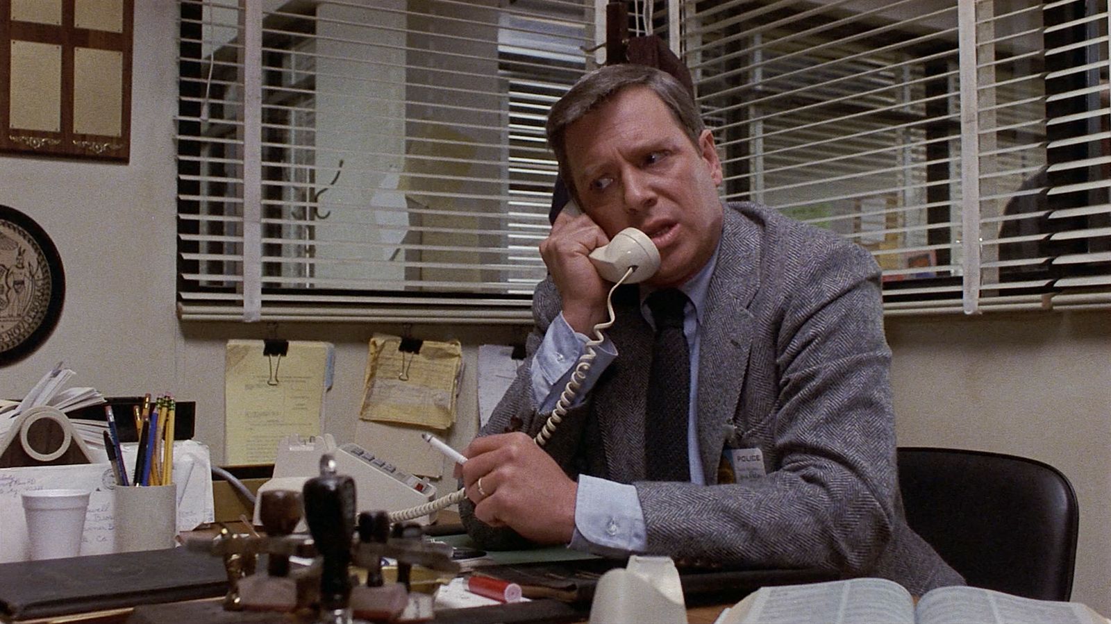 a man sitting at a desk talking on a phone